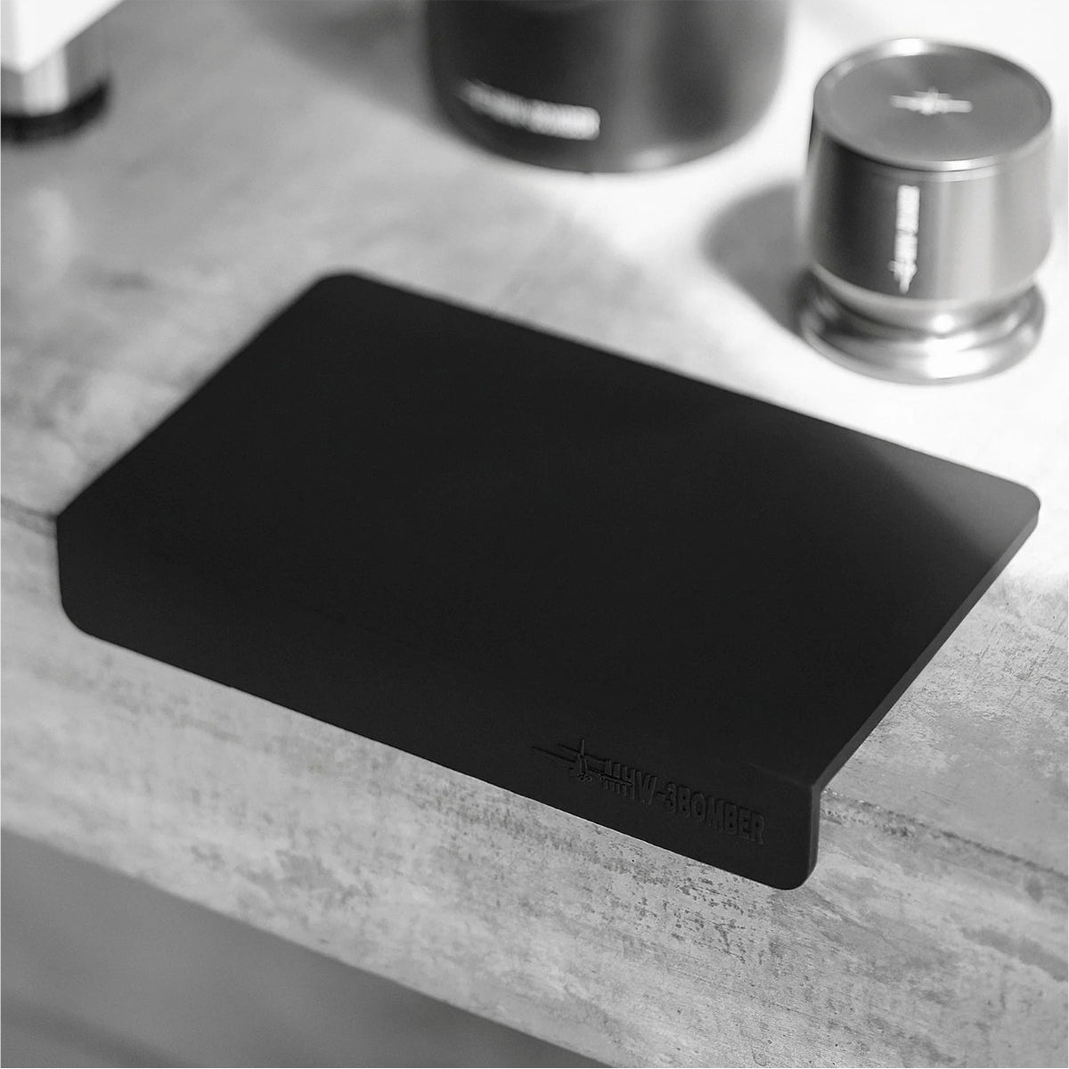 Tapete de silicona MHW-3BOMBER 235x145mm negro sobre barra de café junto a tamper