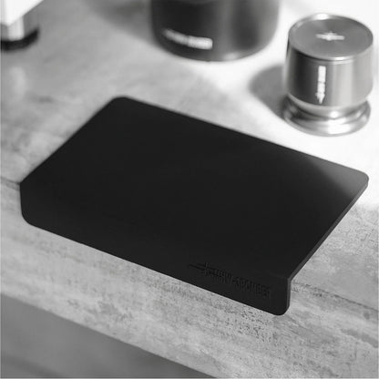 Tapete de silicona MHW-3BOMBER 235x145mm negro sobre barra de café junto a tamper